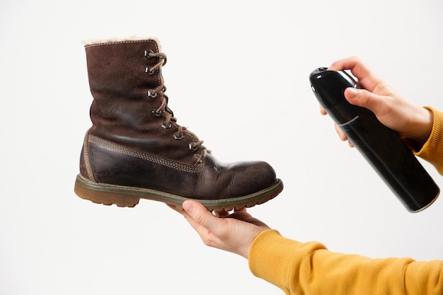A woman applies the spray to brown nubuck womens winter boots