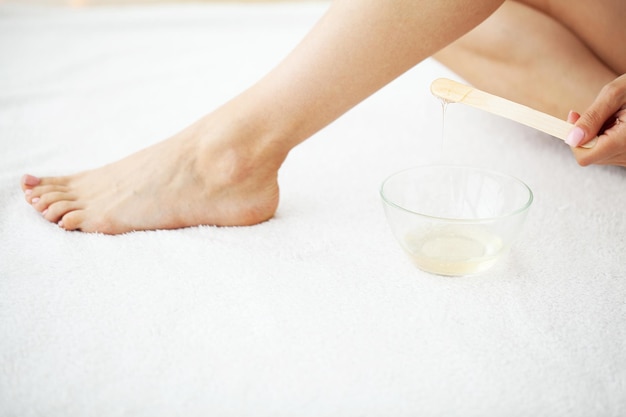 Woman applies wax to her leg to remove hair