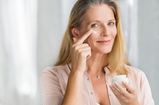 Photo woman applying anti aging lotion on face