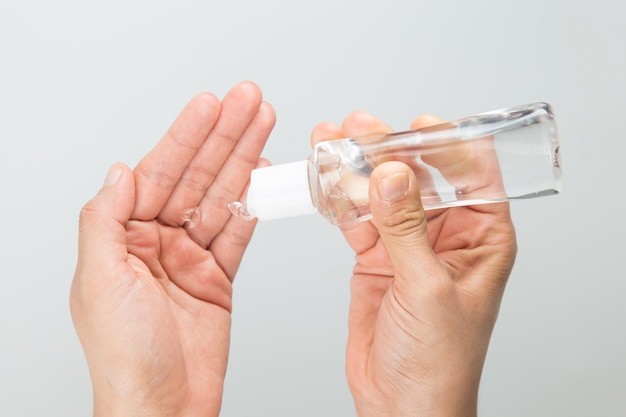 Woman applying antibacterial gel in hands close up, isolated in light gray background