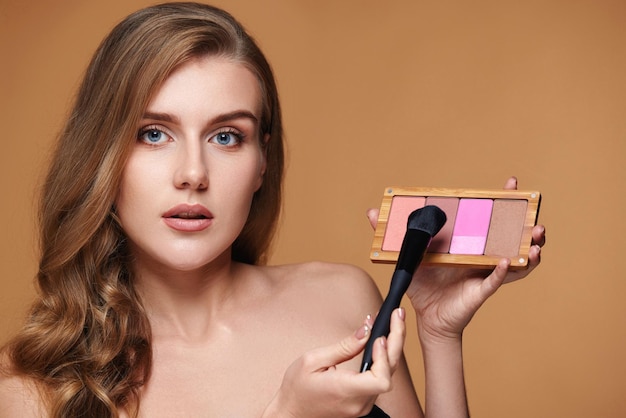 Photo woman applying blush on cheekbone with makeup brush