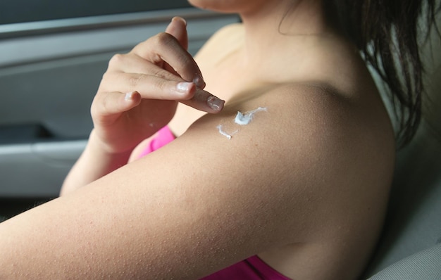 Woman applying cream on the her body