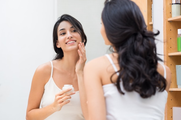 Woman applying cream on her face