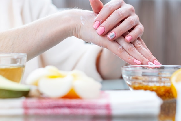 Woman applying the cream on her hands nourishing them with natural cosmetics close-up. Hygiene and care for the skin