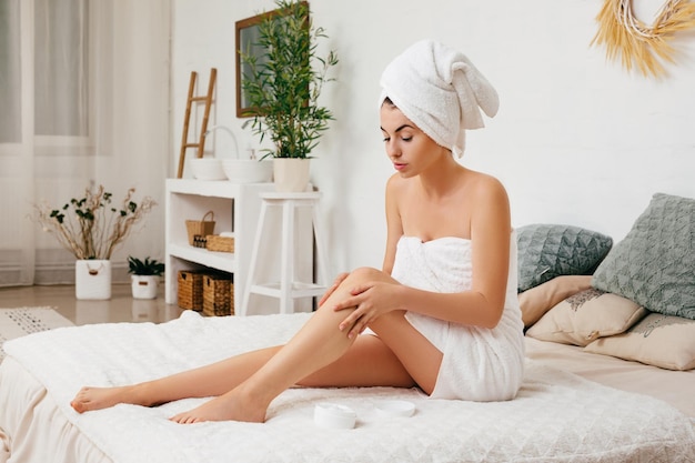 Woman applying cream on her legs