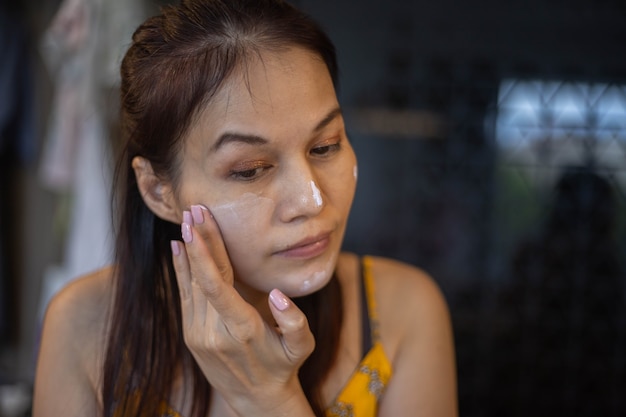 Woman applying cream onto her skin