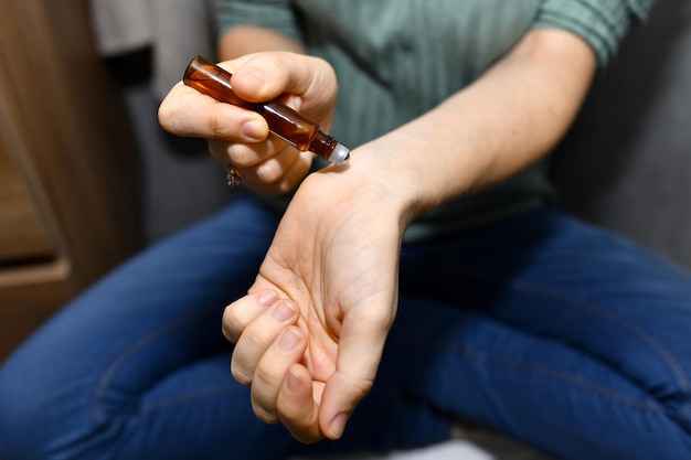 Photo woman applying essential oils on her wrist at home personal skin care