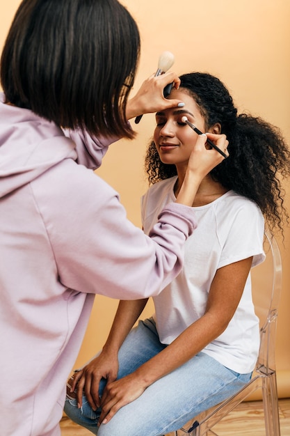 woman applying eyeliner to female