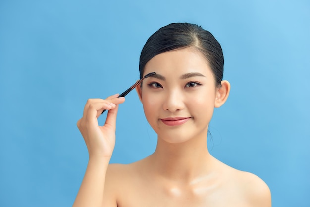 Woman applying eyeshadow on eyelid using makeup brush