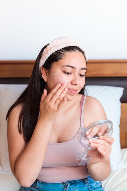 A woman applying a face mask on her face.