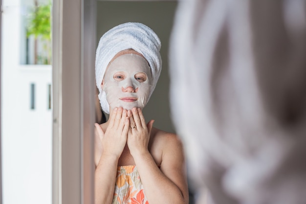 Donna che applica un foglio maschera facciale