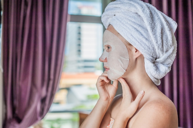 Donna che applica un foglio maschera facciale