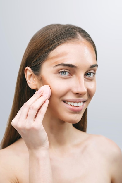 Woman applying foundation on her face