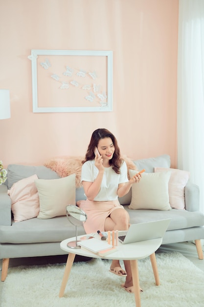 Woman applying her makeup decorative cosmetics and talking on phone.