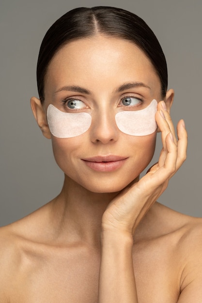 Woman applying hydrogel under-eye recovery patches