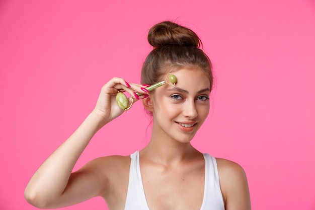 Woman applying jade roller for massaging her face