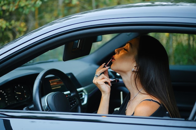 Woman applying lipstick while sitting in the car