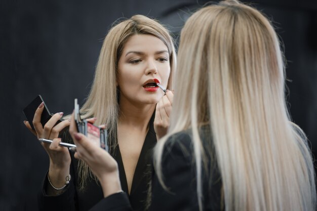 Woman applying liquid lipstick looking to the mirror