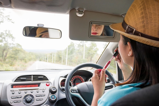 車を運転中のメイクを適用する女性