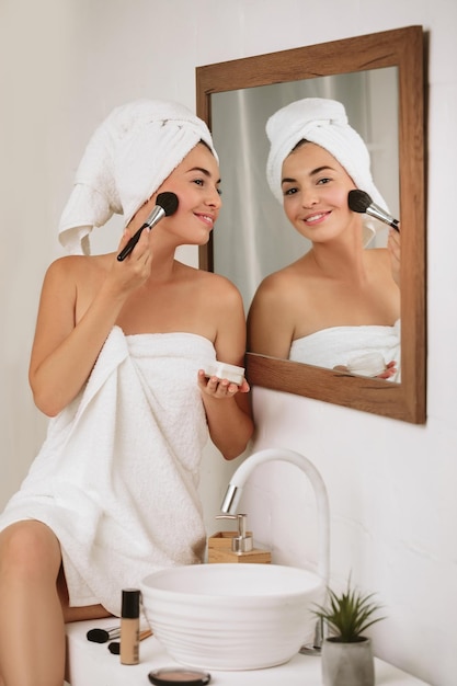 Woman applying makeup on face at home