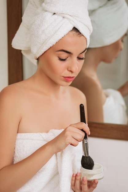 Woman applying makeup on face at home