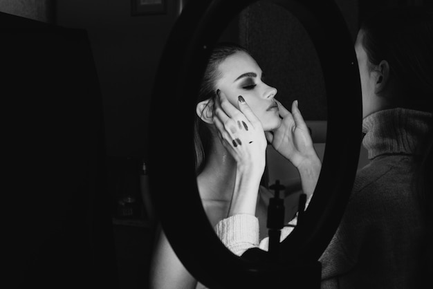 A woman applying makeup in front of a mirror.