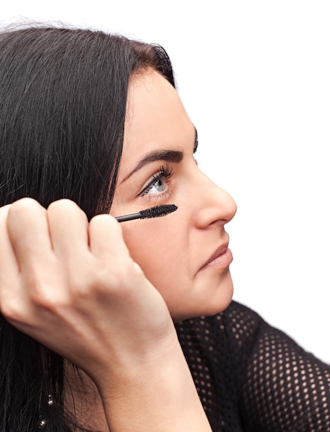 Woman applying mascara on her eyelashes