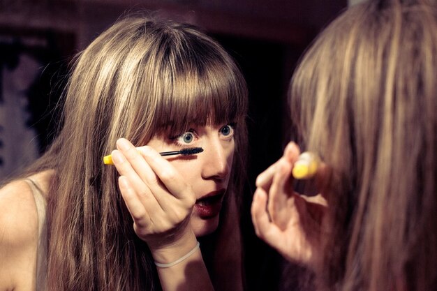 Foto donna che si applica il mascara a casa