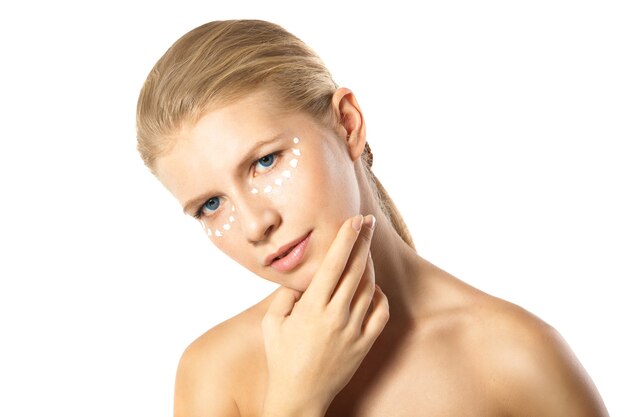 Woman applying moisturizer cream on face isolated