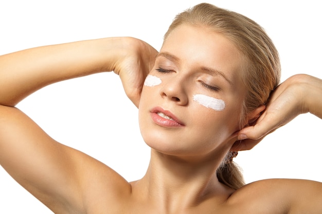 Woman applying moisturizer cream on face isolated