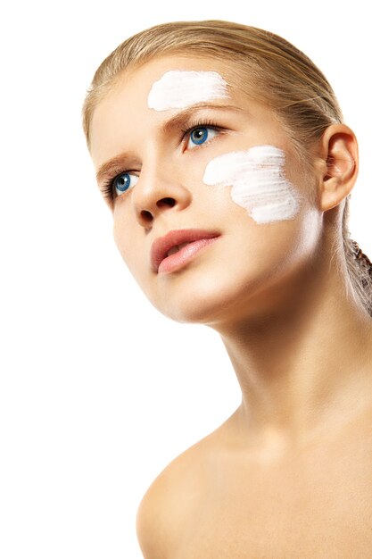 Woman applying moisturizer cream on face isolated