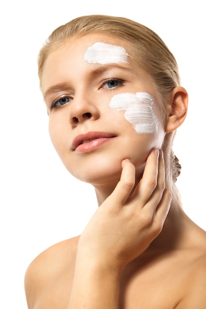 Woman applying moisturizer cream on face isolated