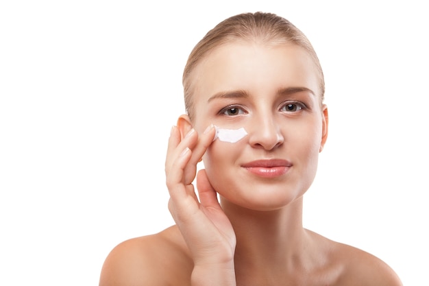 Woman applying moisturizer cream on face isolated