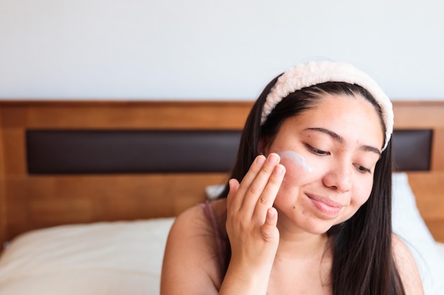 A woman applying a moisturizer on her face.