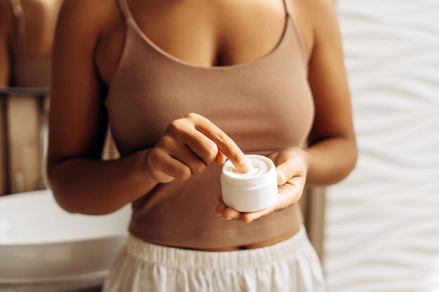 Woman applying moisturizing cream in bathroom