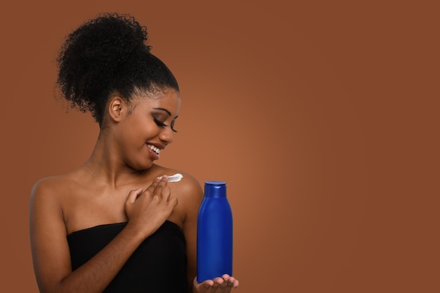 a woman applying moisturizing cream to her skin smiling while holding a bottle demonstrating skin c