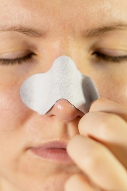 woman applying nose pore strips for blackhead remove deep cleansing with charcoal the treatment for clogged pores vertical photo