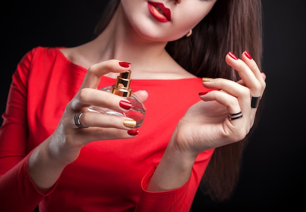 Woman applying perfume on her wrist on black background