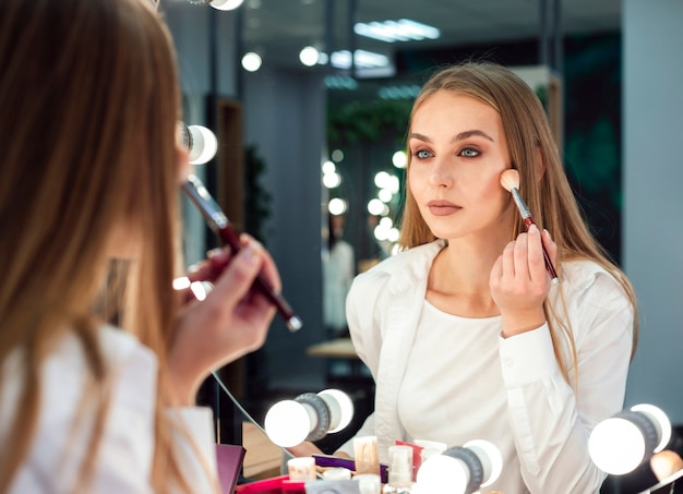 Photo woman applying powder in mirror