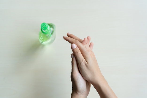 Woman applying sanitizer gel onto her hand for protection against infectious virus, bacteria and germs in wooden background.