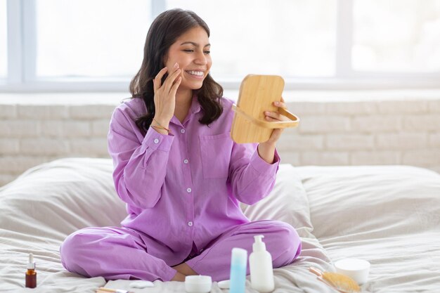 Photo woman applying skincare in bedroom at home