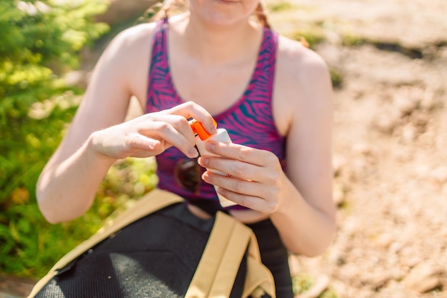 Woman applying sunscreen lotion while sitting at the campsite traveling in the mountains high