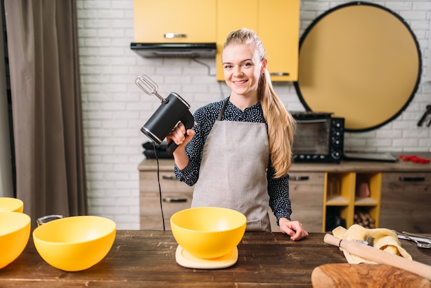 Woman in apron adds sugar into bowl, dough making