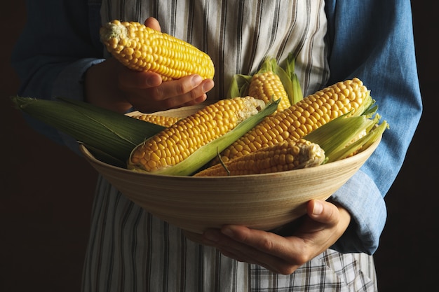 Woman in apron hold bowl of corn against