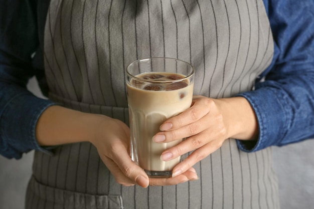 Женщина в фартуке держит стакан с вкусным кофе