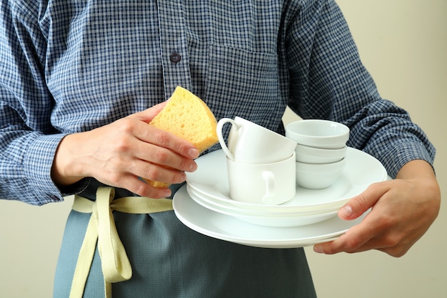 Woman in apron holds clean dishware, close up