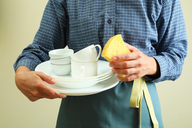 Woman in apron holds clean dishware, close up