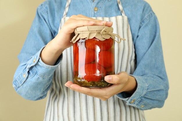 Woman in apron holds jar of pickled tomatoes