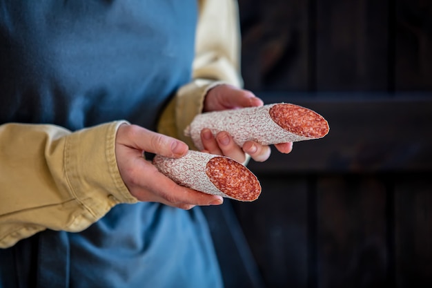 Woman in apron holds salami in hands
