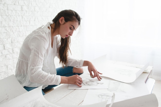 Woman architect lining sketch in studio free space Concentrated female artist working at her workshop copy space on white background Art work creativity talent concept